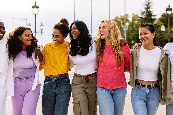 Fröhliche junge Frauen, Arm in Arm, mit diversem Hintergrund
